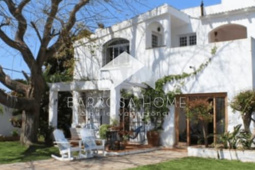 Villa mediterránea blanca Barrosa con ventanas arqueadas, terraza y frondoso jardín en España