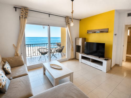 Luminoso salón con vista al mar, pared amarilla, balcón frente a la playa y vistas al océano en El Calón Playa