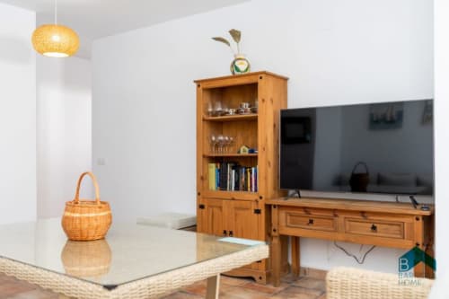 Sala moderna de Barrosa Home con muebles de madera, cesta tejida, lámpara colgante y televisor de pantalla plana