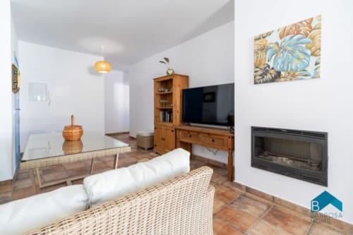 Sala de estar moderna en Barrosa Home con chimenea, televisión, muebles de mimbre y arte tropical