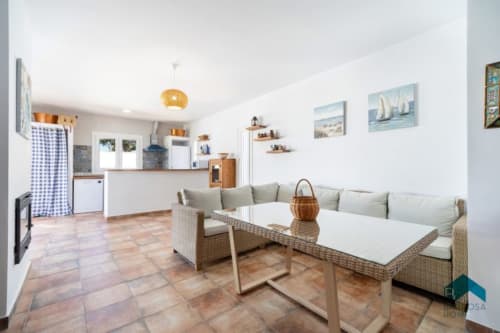 Salón abierto de Barrosa Home con mobiliario de mimbre, mesas blancas, suelo de terracota y decoración costera en España