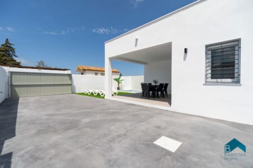 Casa blanca moderna con patio cubierto, comedor y garaje en Barrosa Home en España bajo cielo despejado