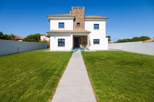 Villa moderna Barrosa con muros blancos, tejado de barro, jardín impecable y torre de piedra en España