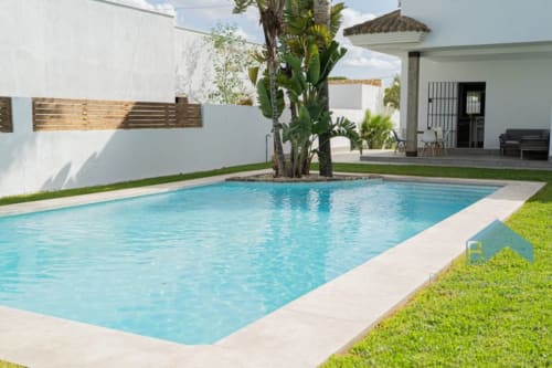 Piscina moderna con palmera en Barrosa Home, España. Casa contemporánea blanca con terraza