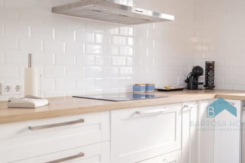 Cocina blanca moderna con encimeras de madera en la casa de vacaciones Barrosa Home en España