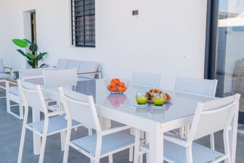 Moderner Außenessbereich im Barrosa Home mit weißen Möbeln, frischem Obst und grünen Pflanzenelementen