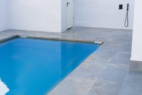 Modernes Hallenbad in Barrosa Home mit blauem Wasser, grauem Fliesenbelag, weißen Wänden und Duschen in Spanien.