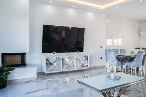 Modernes Wohnzimmer im Barrosa Home mit Flachbildfernseher, weißem X-Muster-Schrank, Marmorboden, Kamin und Essbereich