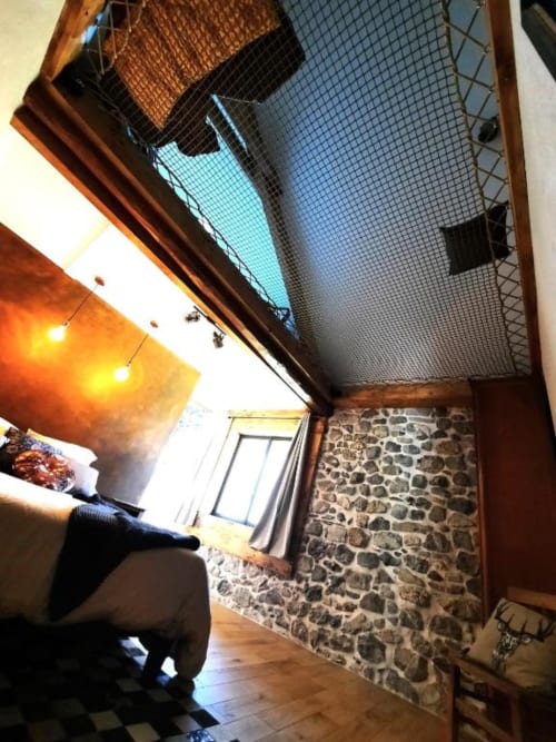 Chambre L'Atelier de Paul au Petit Bégou avec murs en pierre, parquet et vue sur le jardin à Saint-Auban-d'Oze