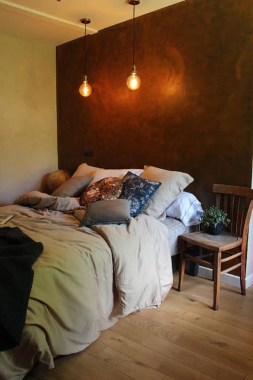 Chambre cosy du Petit Bégou avec mur accent rouille, luminaires suspendus et mobilier bois à Saint-Auban-d'Oze