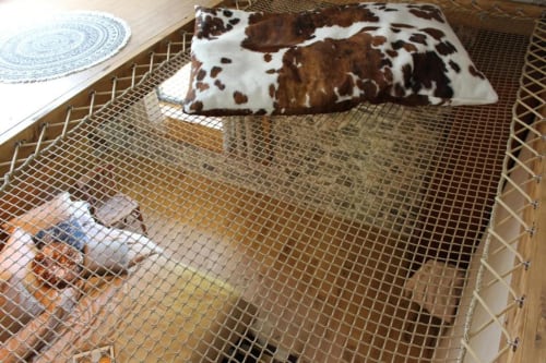 Chambre accueillant les animaux au Petit Bégou avec coussin en peau de vache, parc grillagé et vue sur le jardin