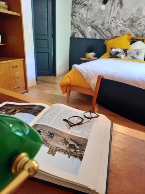 Chambre douillette au Petit Bégou avec livre ouvert, lunettes et touches de jaune donnant sur le jardin
