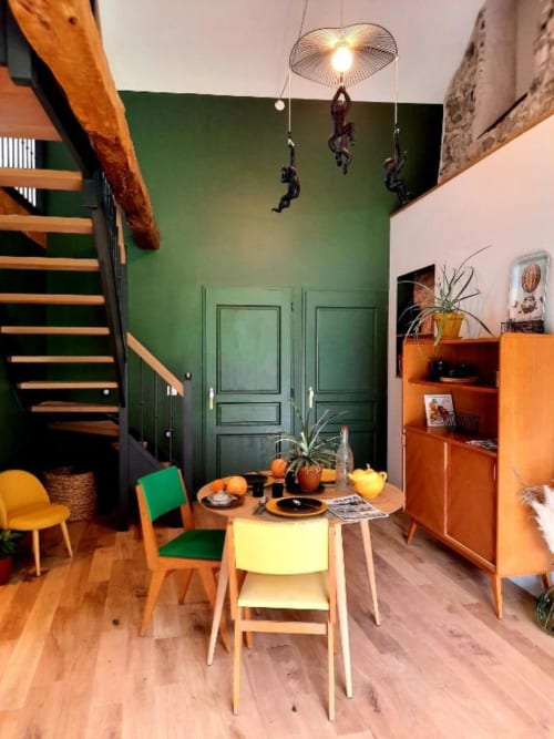 Salle à manger colorée de l'appartement L'Auberge de Marie au Petit Bégou avec escalier en bois, murs verts et style années 50