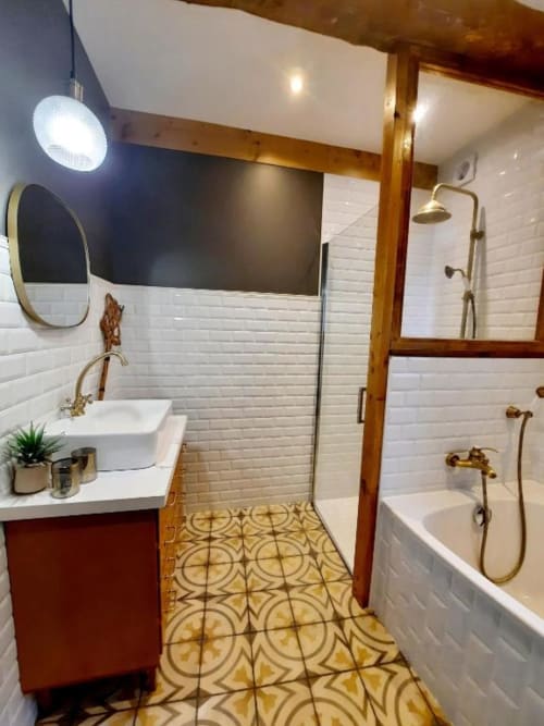 Salle de bains moderne du gîte L'Auberge de Marie au Petit Bégou avec carrelage métro blanc, robinetterie laiton et sol à motifs