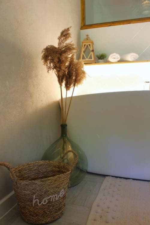 Herbe de pampa séchée dans un vase vert avec panier tressé à la salle de bain du B&B Le Petit Bégou, Saint-Auban-d'Oze