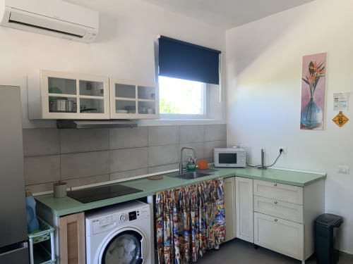 Cucina moderna nell'appartamento Terra di Ca' Salino B&B con piani di lavoro verdi, lavatrice, armadi bianchi e vista sul giardino