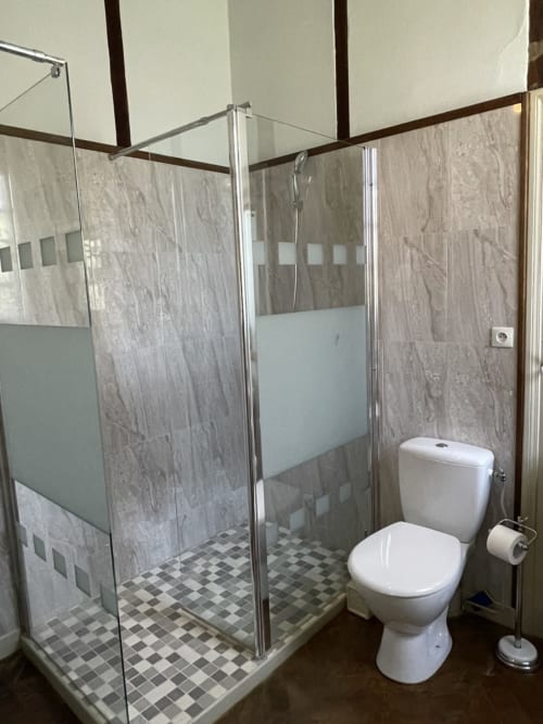 Salle de bain moderne au Gîte Voltaire du Château de la Motte avec douche à l'italienne, toilettes blanches et carrelage à damier