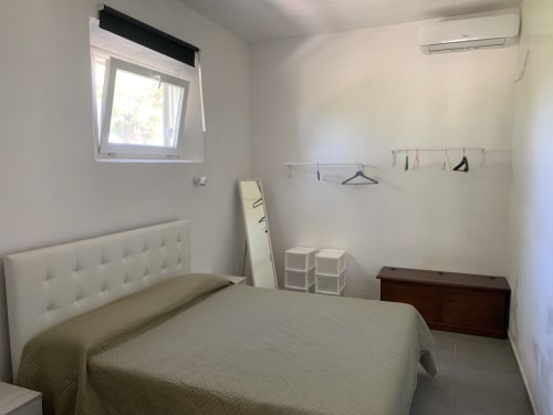 Camera da letto luminosa nell'appartamento Ca' Salino Terra con letto bianco, finestra con vista sul giardino, aria condizionata e arredi minimali