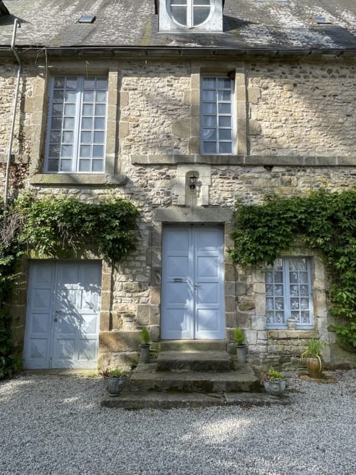 Façade de chaumière au Château de la Motte avec portes bleues, fenêtres à guillotine et lierre, Joué-du-Plain