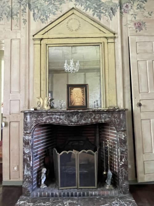Élégante cheminée aux encadrements en marbre noir et miroir orné à la Gîte Voltaire du Château de la Motte, Joué-du-Plain