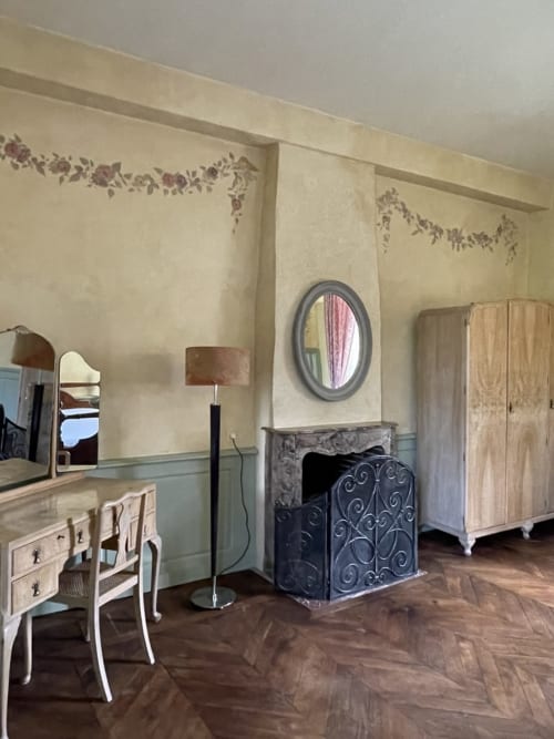 Chambre élégante du Château de la Motte avec cheminée, mobilier d'époque et vue sur les jardins