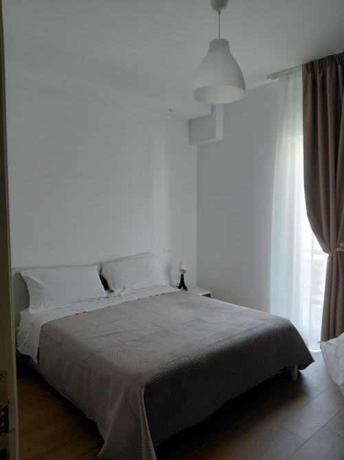 Camera minimalista del Makasa B&B a Villapiana con letto, lampada a sospensione e tende marroni