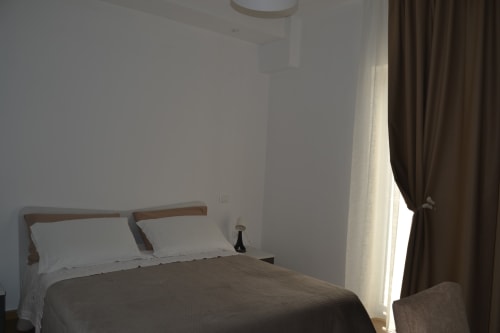 Camera moderna al Makasa B&B di Villapiana con letto in legno, biancheria bianca e tende marroni