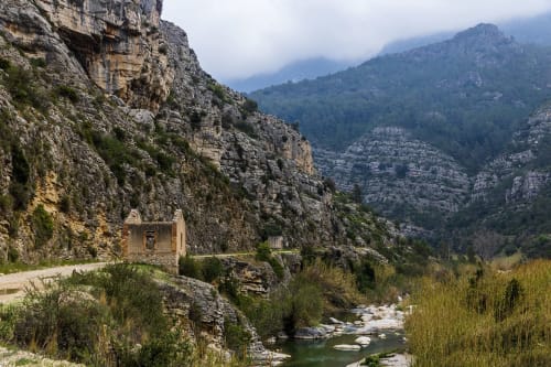 Cañón de montaña rocosa con construcción de piedra y arroyo cerca de La Caseta de Ròtova, España