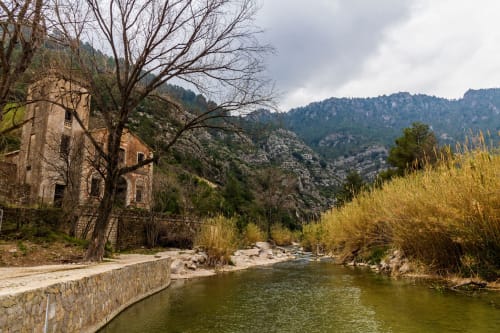 Alojamiento de montaña Ròtova con vistas al río, edificio histórico de piedra en paisaje de valle español