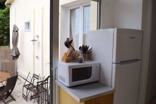 Modern villa kitchen at Hôtel l'Orangeraie Lavandou with white refrigerator, microwave, and knife block near garden view
