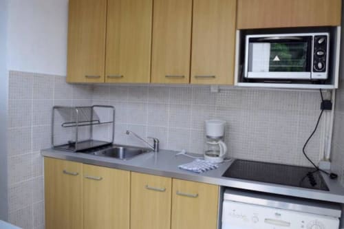 Modern kitchen in Le Lavandou villa with yellow cabinets, microwave, coffee maker, and stainless steel sink