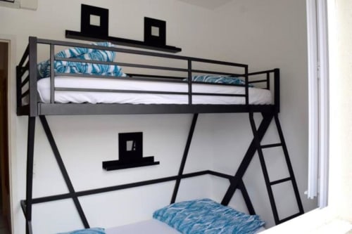Modern black metal bunk bed with blue patterned bedding in holiday villa at Hôtel l'Orangeraie Lavandou, Le Lavandou