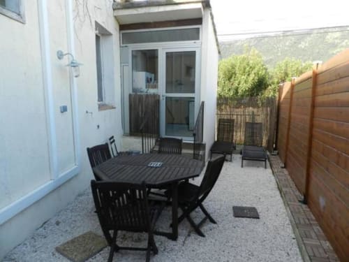 Private patio area with black dining table and chairs at Hôtel l'Orangeraie Lavandou villa, wooden fence, hillside views