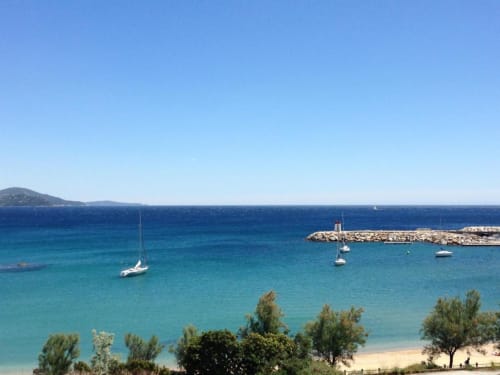 Turquoise Mediterranean waters with sailboats near Le Lavandou beach and harbor, French Riviera
