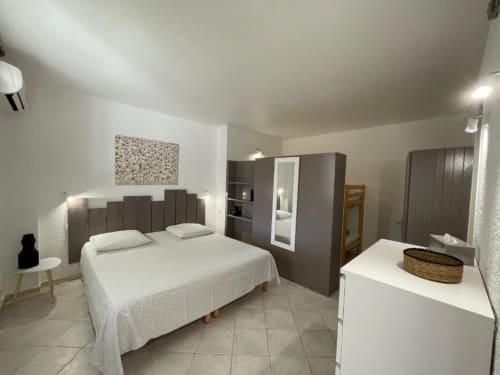 Chambre moderne à l'Hôtel l'Orangeraie Lavandou avec lit queen-size, tête de lit grise et coin cuisine au Lavandou