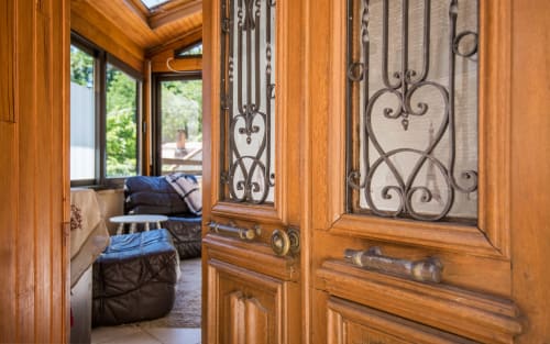 Wooden doors with decorative iron grilles open to Dourbie Cottage in Millau, revealing mountain views and modern amenities