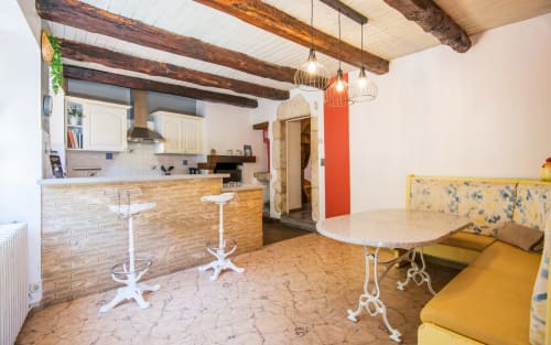 Modern open-plan kitchen and dining area with exposed beams, brick backsplash, and colorful accents in Dourbie Cottage,