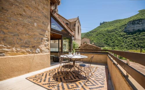 Dourbie Cottage terrace in Millau with mountain views, dining table, stone architecture