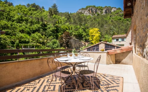 Panoramic terrace with dining table overlooking green mountains and Millau valley at Dourbie Cottage