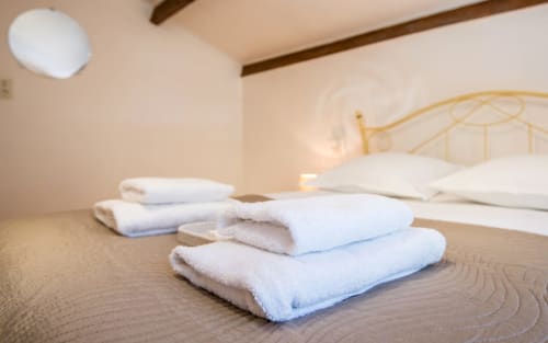 Fresh white towels arranged on wooden floor in Dourbie Cottage bedroom with golden bed headboard, Millau hotel