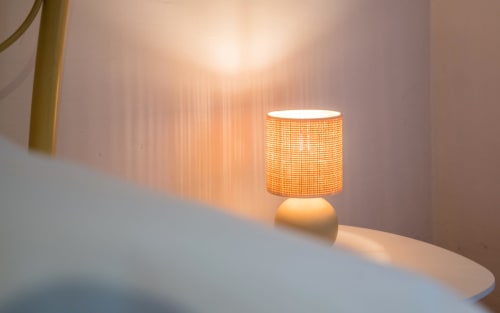 Warm-lit table lamp with woven shade in Dourbie Cottage apartment at La Conciergerie, Millau