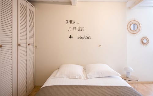 Cozy bedroom in Dourbie Cottage, Millau with French wall text, white bedding, louvered closet, and decorative wall mirrors