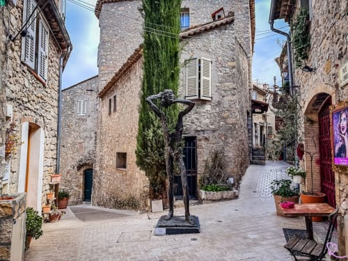 Historic stone courtyard in Spéracèdes with sculpture, potted flowers, and traditional buildings at Pipa Polaris guesthouse