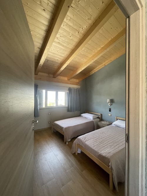 Camera luminosa con travi in legno a Villa Maria, Cosenza con due letti e luce naturale