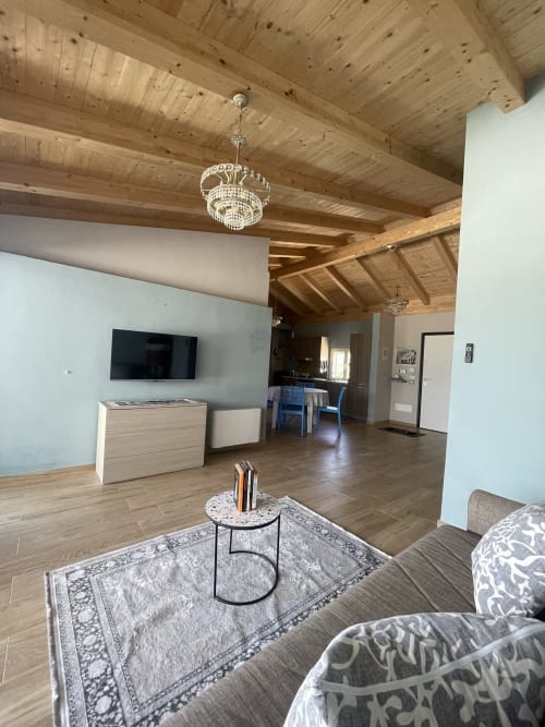 Soggiorno moderno a Villa Maria con travi in legno a vista, lampadario di cristallo e vista sulla campagna di Cosenza