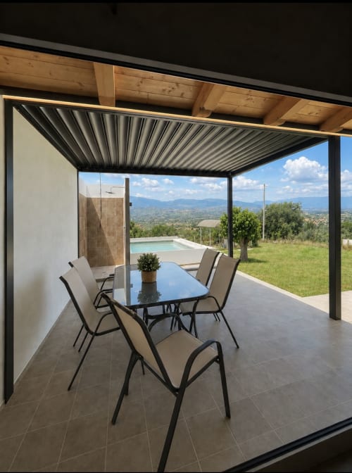 Patio coperto moderno a Villa Maria con tavolo da pranzo, sedie lounge, piscina e vista sulle montagne della Calabria