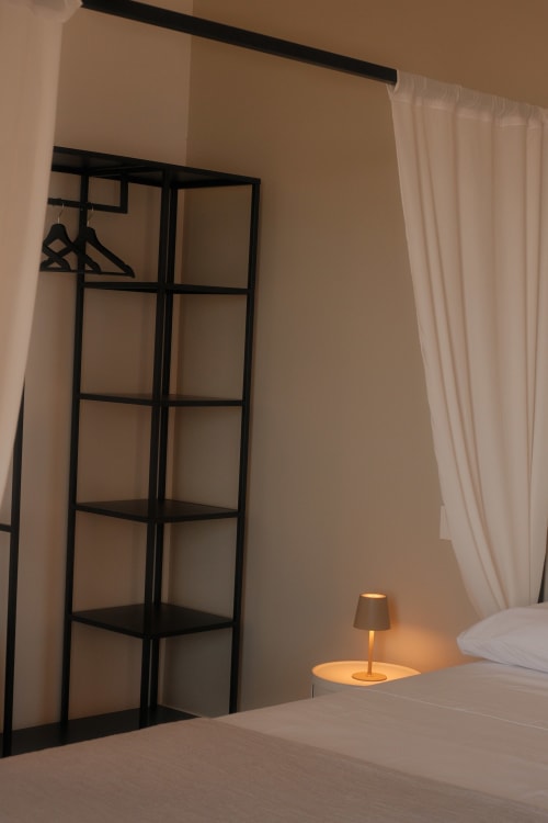Modern bedroom at Nafura hotel in Raffadali with black geometric room divider, cream curtains, and bedside lamp