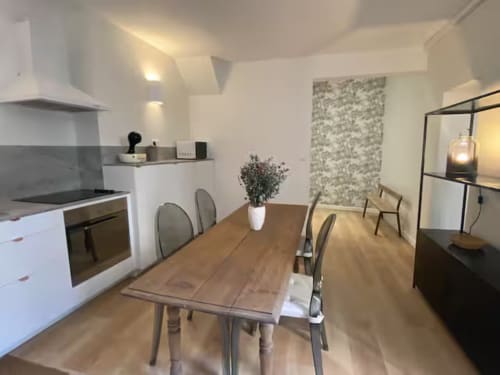 Cuisine-séjour moderne de l'appartement Mattbnb Metz avec table en bois, mobilier blanc et décoration contemporaine