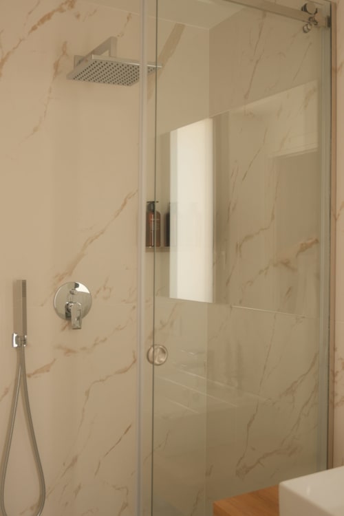 Modern shower enclosure with marble-effect tiles at Nafura hotel in Raffadali, featuring rainfall showerhead and handheld