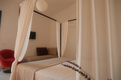 Canopy bed in Amira room at Nafura hotel, Raffadali with cream drapes and lounge seating